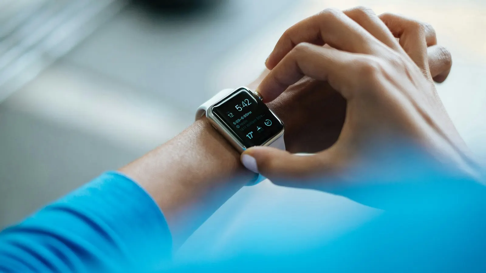 A person tapping an Apple Watch on their wrist.