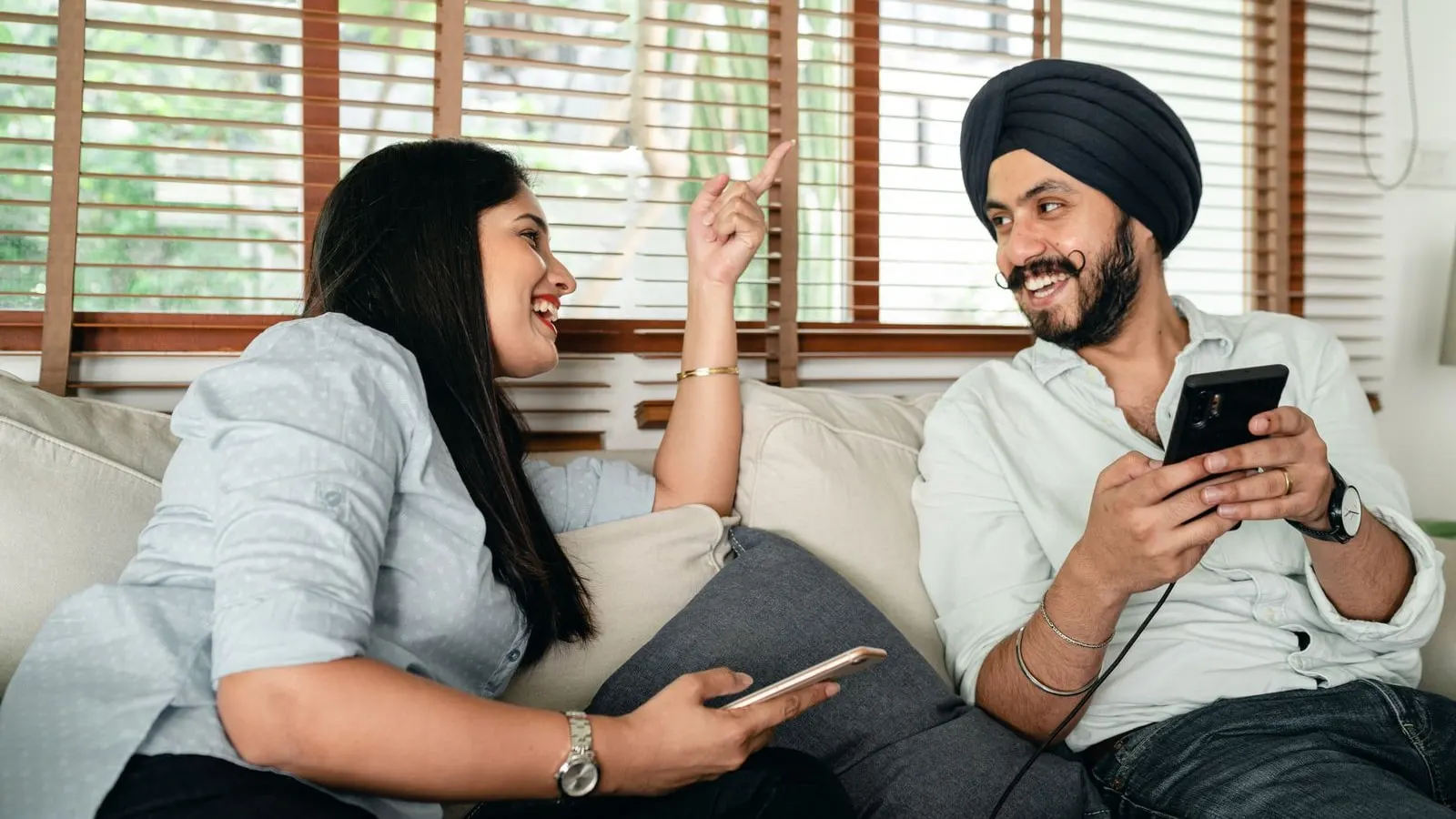 A couple at home, each holding their own phone.
