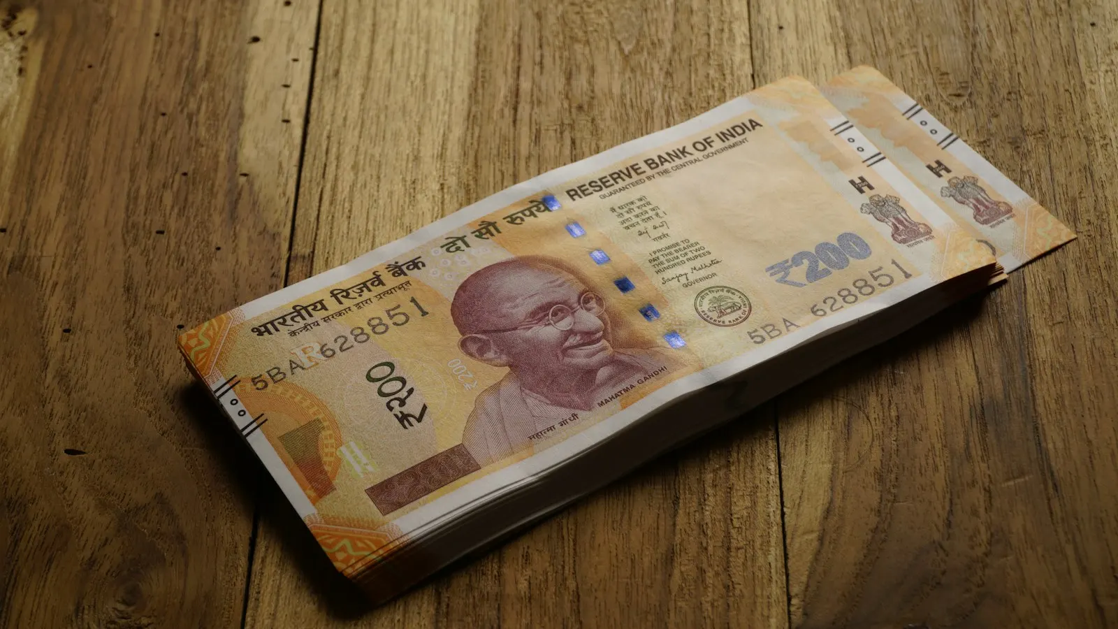 Indian rupee notes on a wooden table.