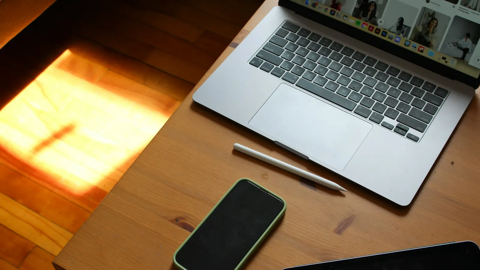 A MacBook, iPad, and iPhone on a wooden desk.